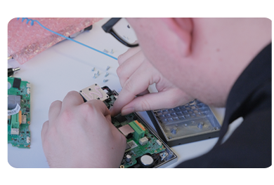 CIE Group technician repairing and testing electronic access control equipment at a workbench