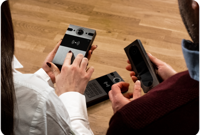 Two people examining smart access control and intercom devices, including a keypad, card reader and video door unit