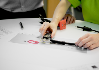 Technician testing and measuring electronic components and cabling on a technical workbench